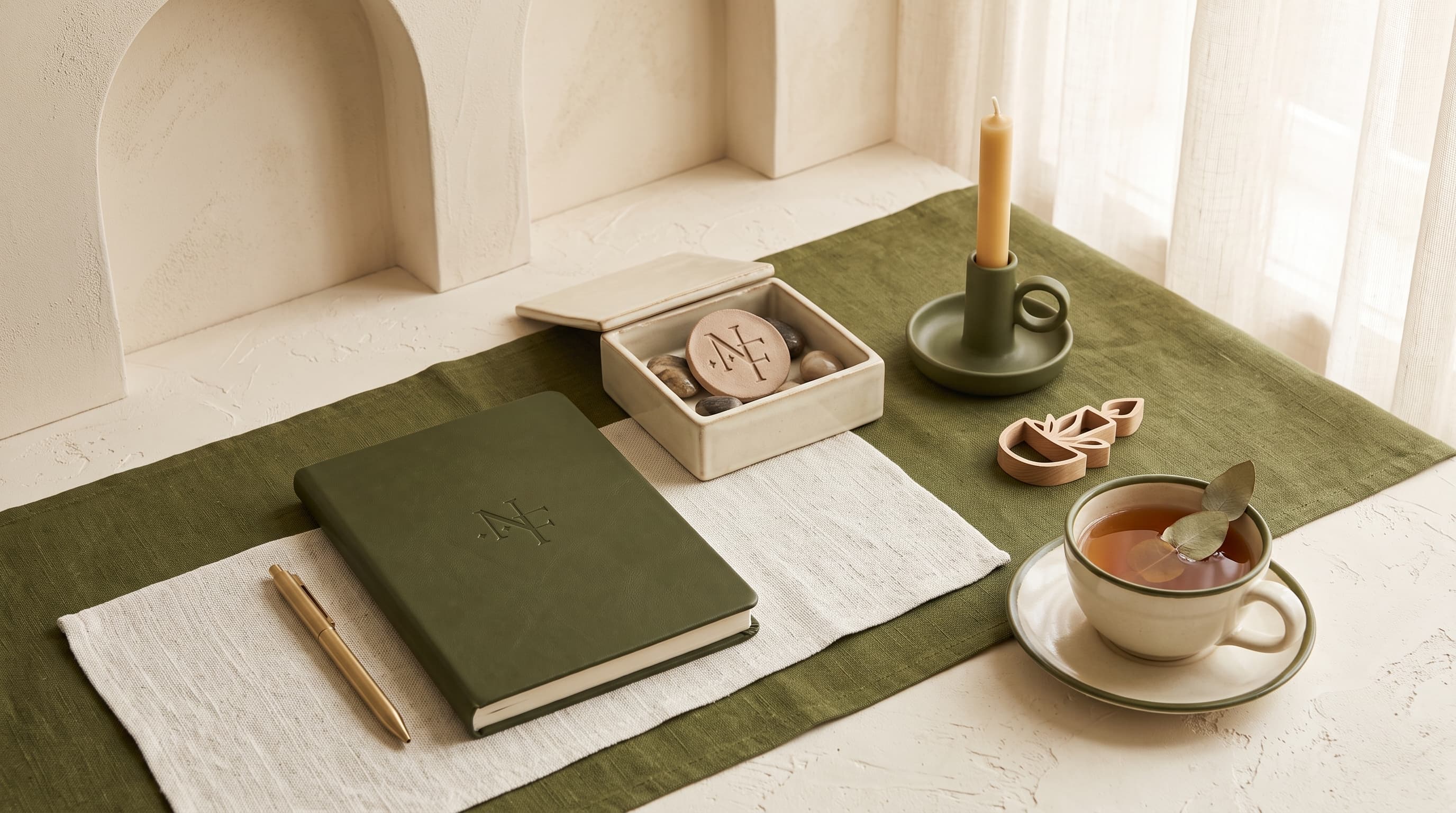 An open Naylah desk scene with journal, candle, and tea